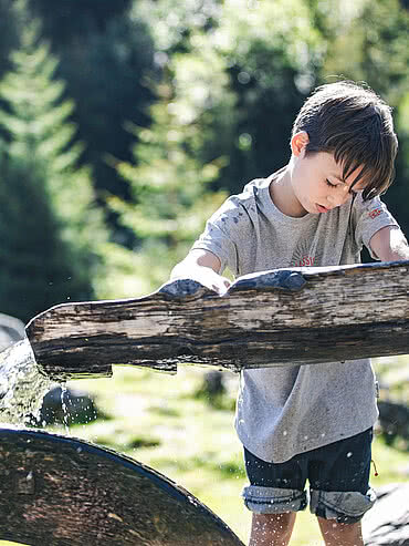 Boy playing with a water wheel at the head of the valley in Saalbach Hinterglemm