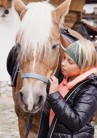 Kind mit Pferd im Pferdestall vom Hotel Unterschwarzachhof